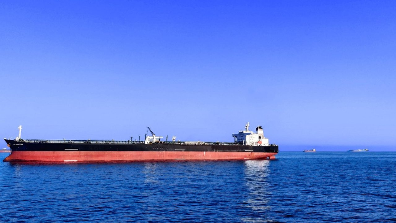 A large crude oil tanker sailing through open ocean waters under a cloudy sky.