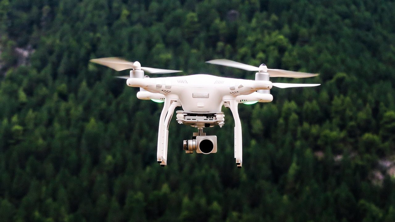 A small quadcopter drone photographed against a grey overcast sky.
