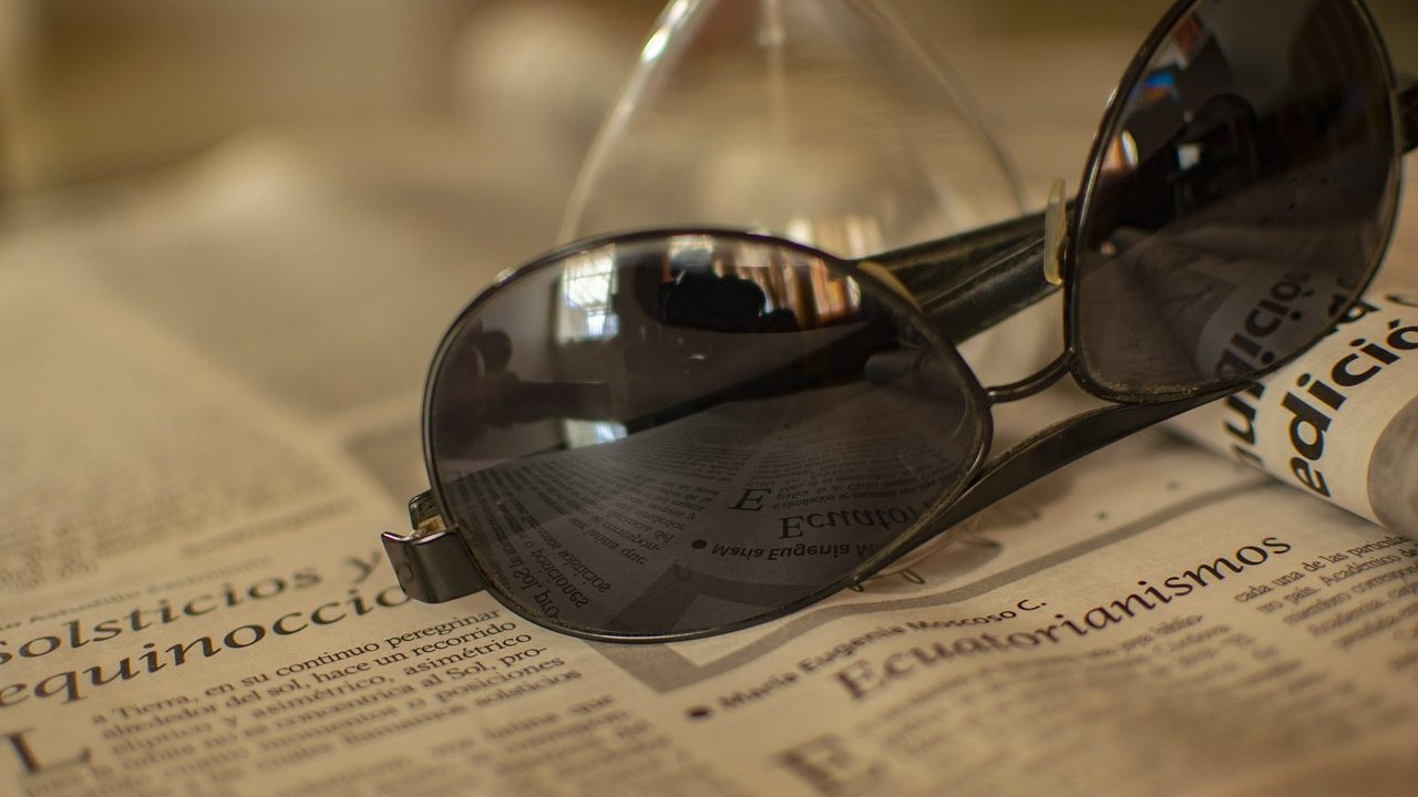 A physical globe and folded newspapers rest on a wooden desk under warm office lighting.