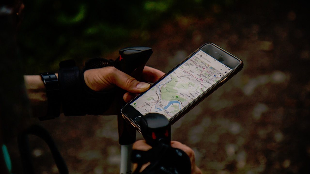 A GPS navigation device displays a blue route line across a digital map with location markers.