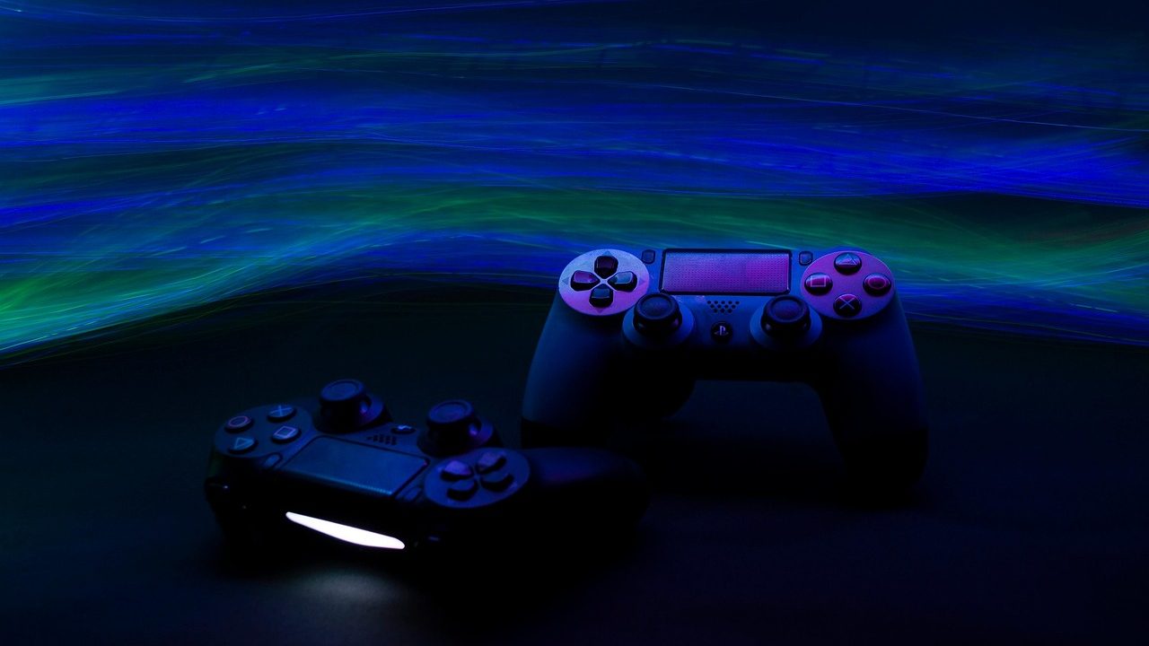A modern video game controller resting on a surface, lit by blue ambient light.