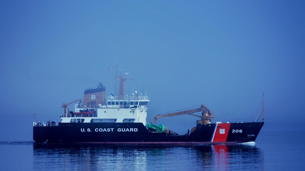 A white and orange Coast Guard patrol vessel underway on open water.