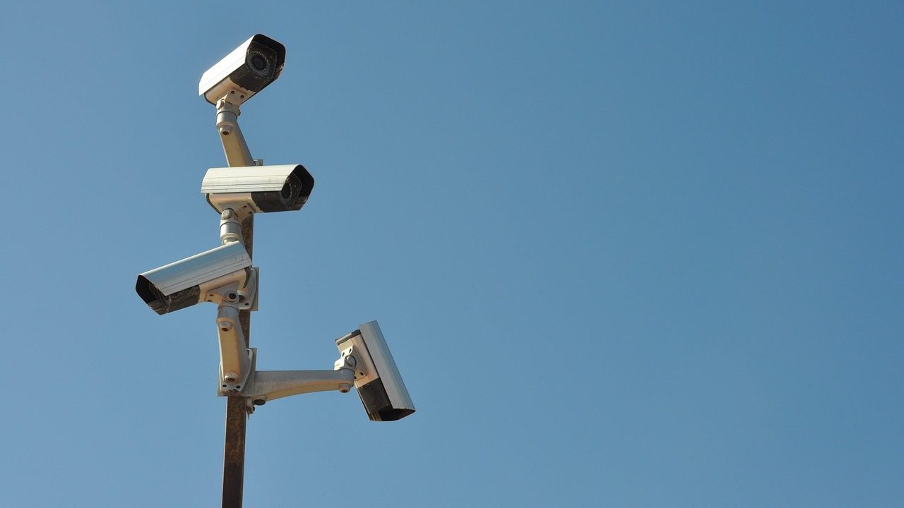 A security camera mounted on a pole overlooking a parking area.