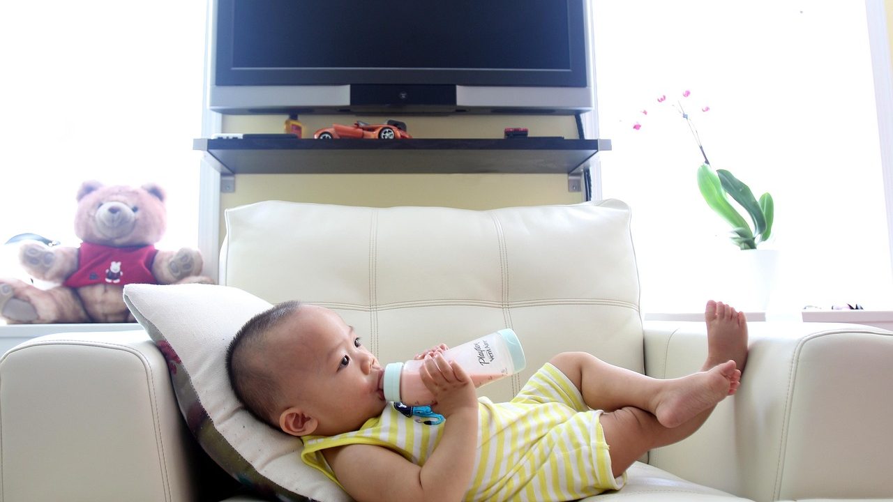A white baby bottle and infant formula container resting on a wooden surface.