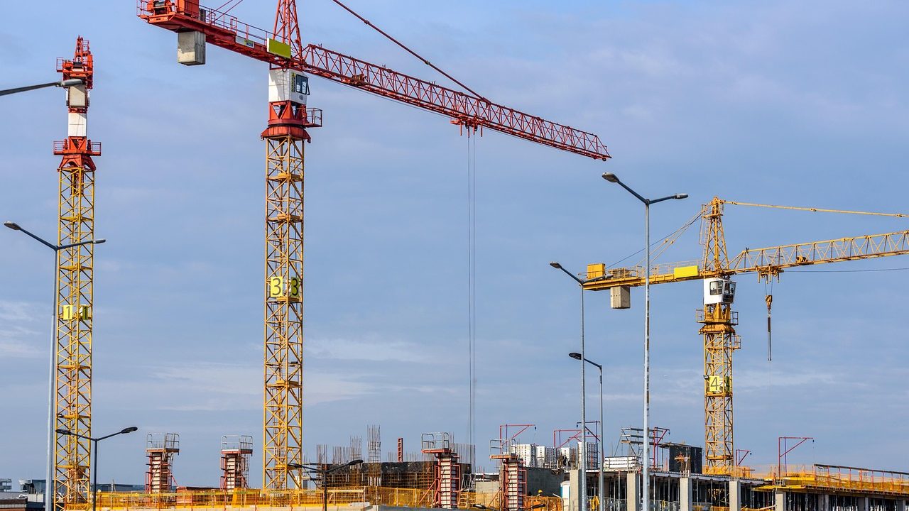 A multifamily residential building under construction with scaffolding and framing visible.