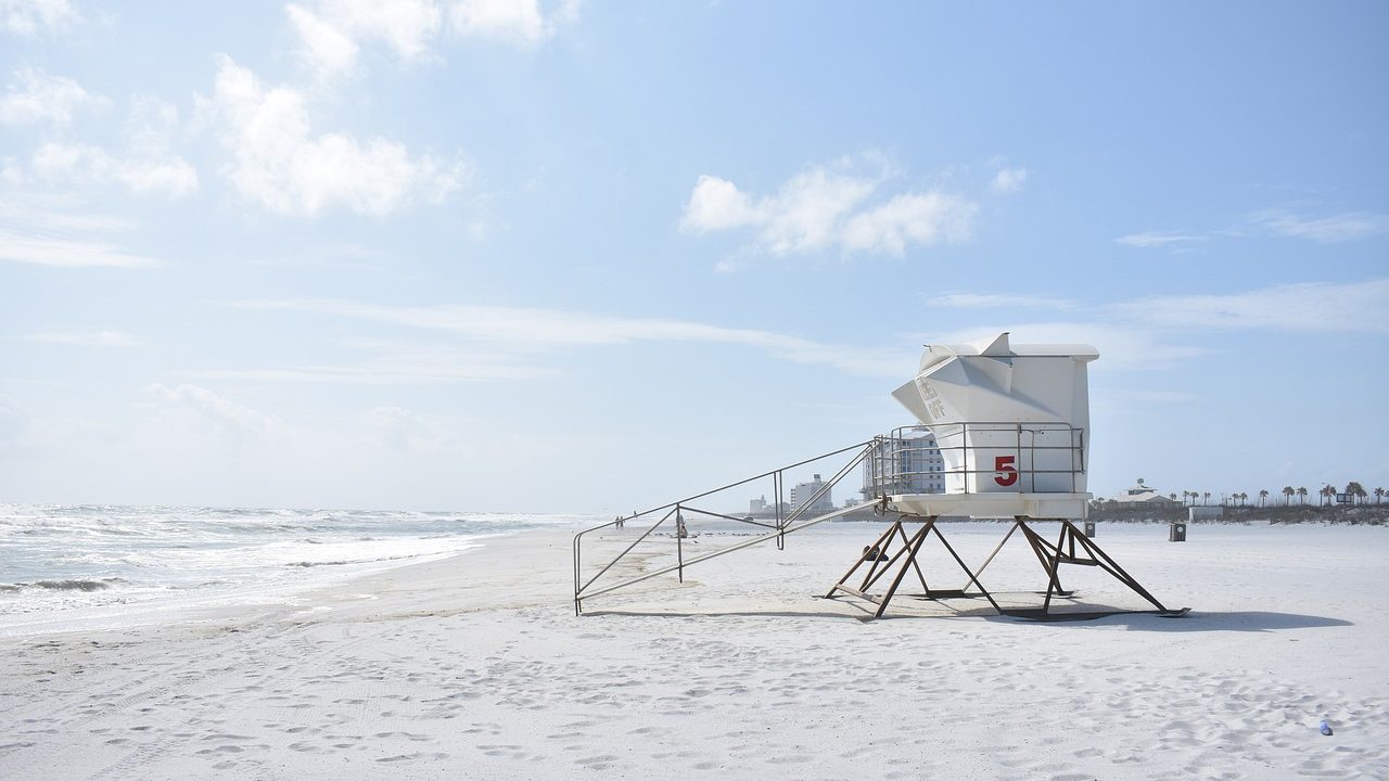 Red lifeguard tower standing on a sandy beach with waves breaking in the background