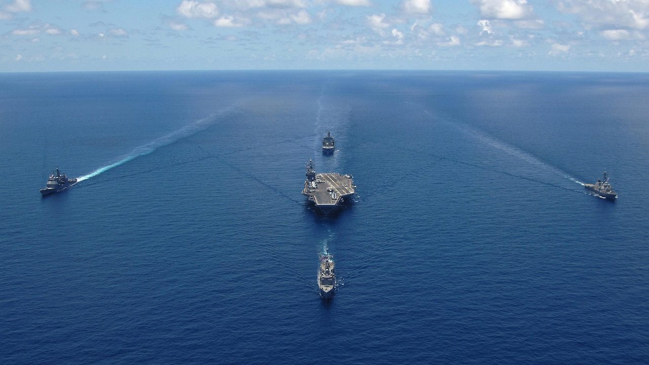 A gray Navy ship underway on open ocean under overcast skies.
