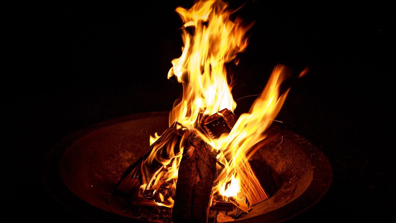 A small tabletop fire pit glowing orange at dusk on an outdoor patio.