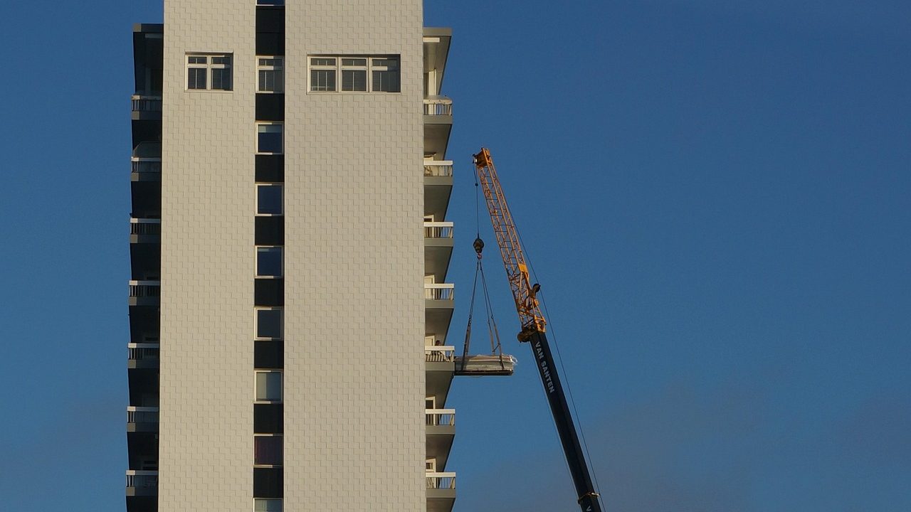A multi-story apartment building under construction with scaffolding and cranes.