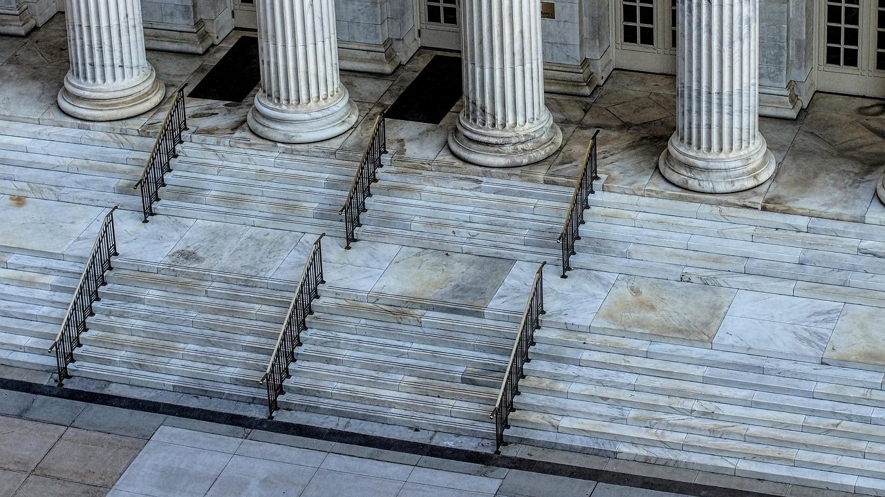 Wide stone steps leading up to the entrance of a courthouse with tall columns.