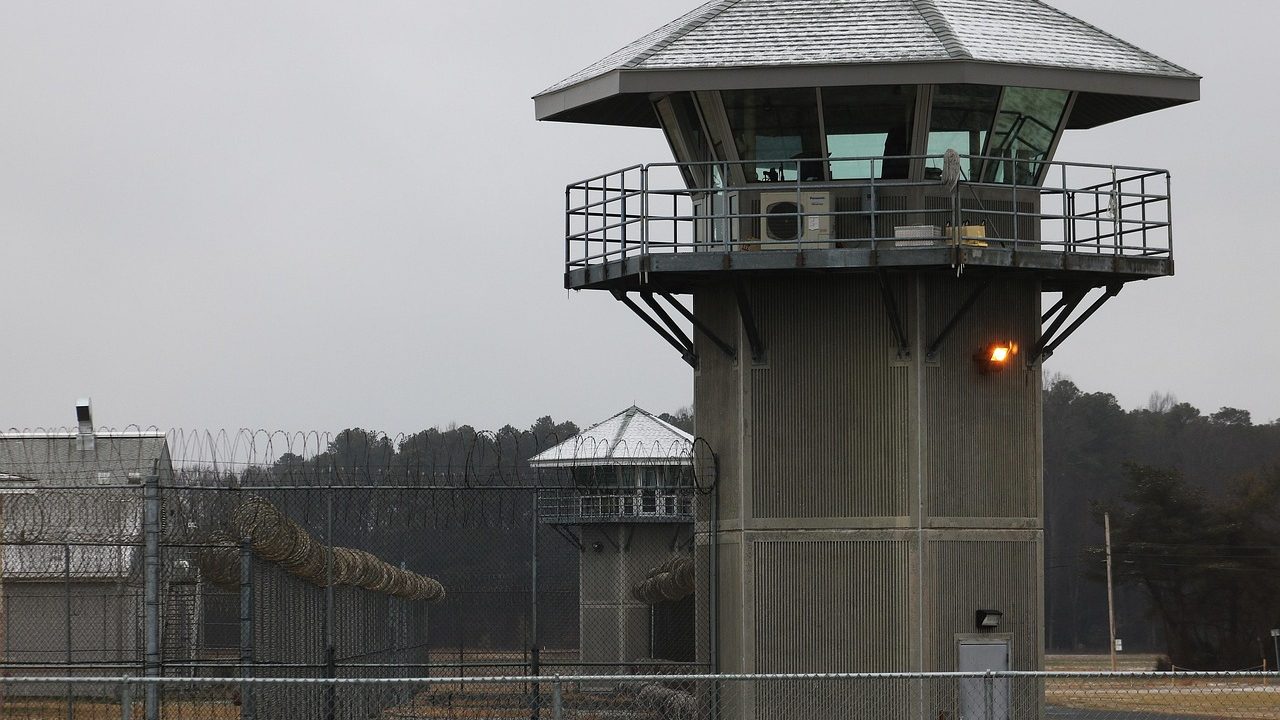 Chain-link fencing topped with razor wire surrounding the perimeter of a large institutional facility.
