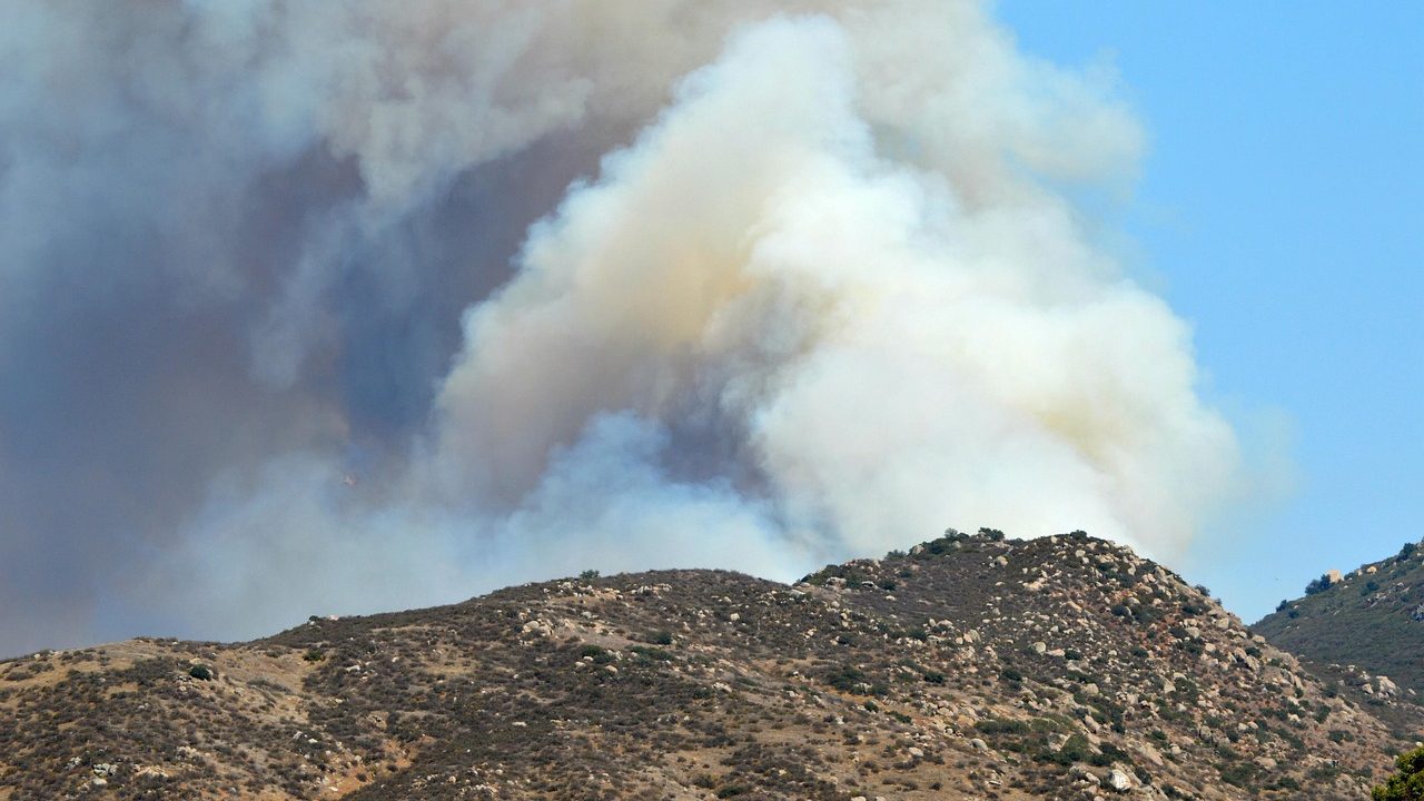 An orange smoke-filled sky over dry California hills on a hot summer day.