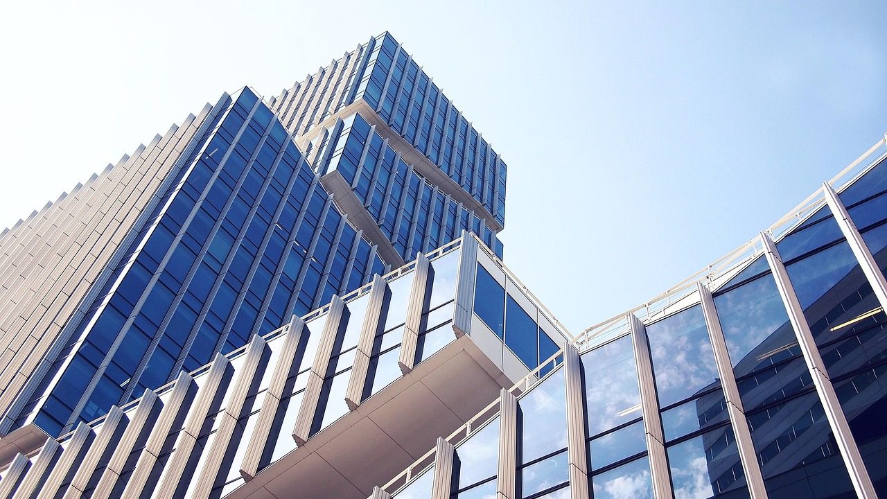 Glass office towers reflecting blue sky in a modern urban business district.
