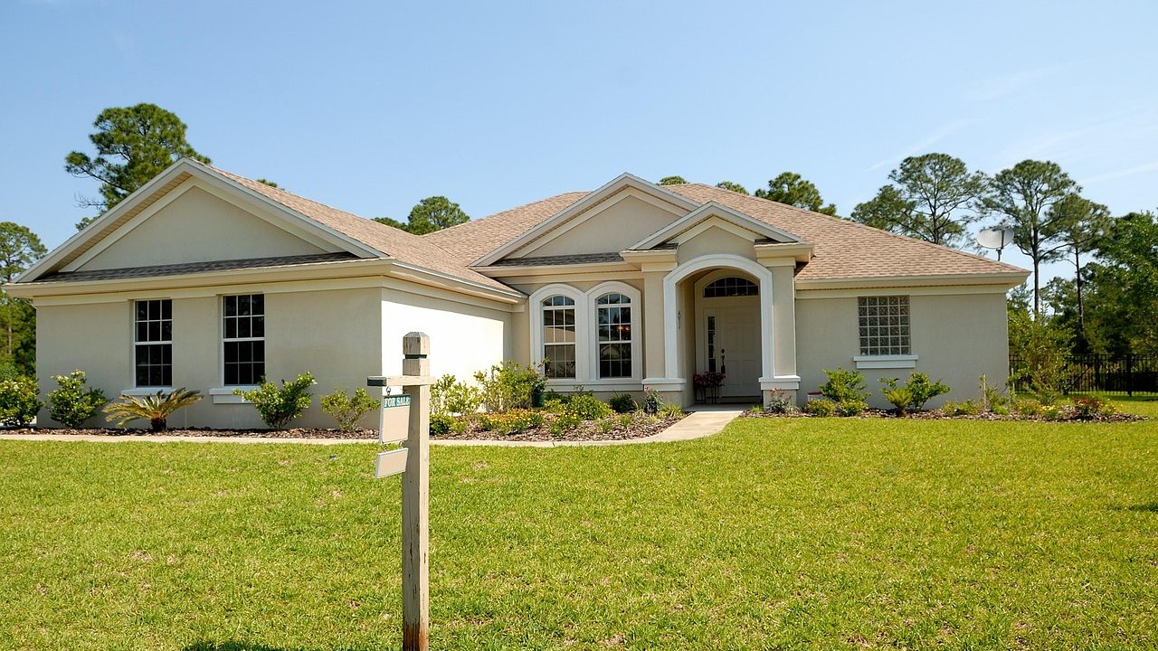 A row of suburban houses with a for-sale sign posted in a front yard.