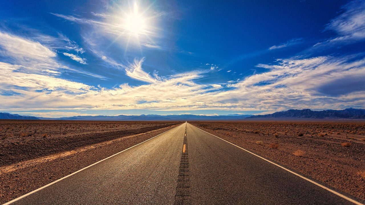 Heat shimmer rising from a sun-baked desert road under a cloudless sky.