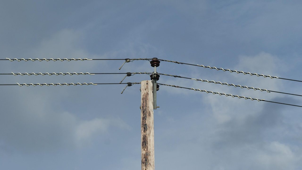 High-voltage power transmission lines stretching across an open sky at dusk.