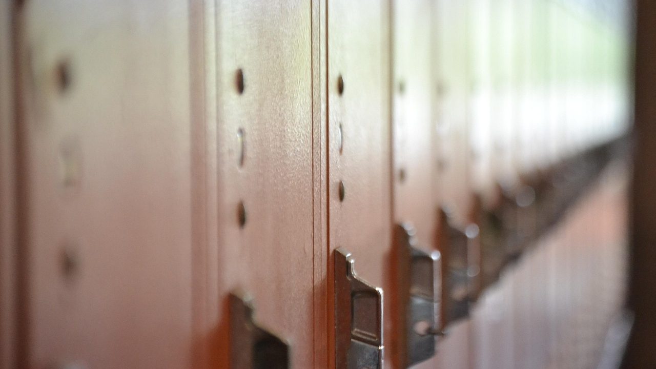 Students walk through a bright school hallway lined with lockers on the first day of class.