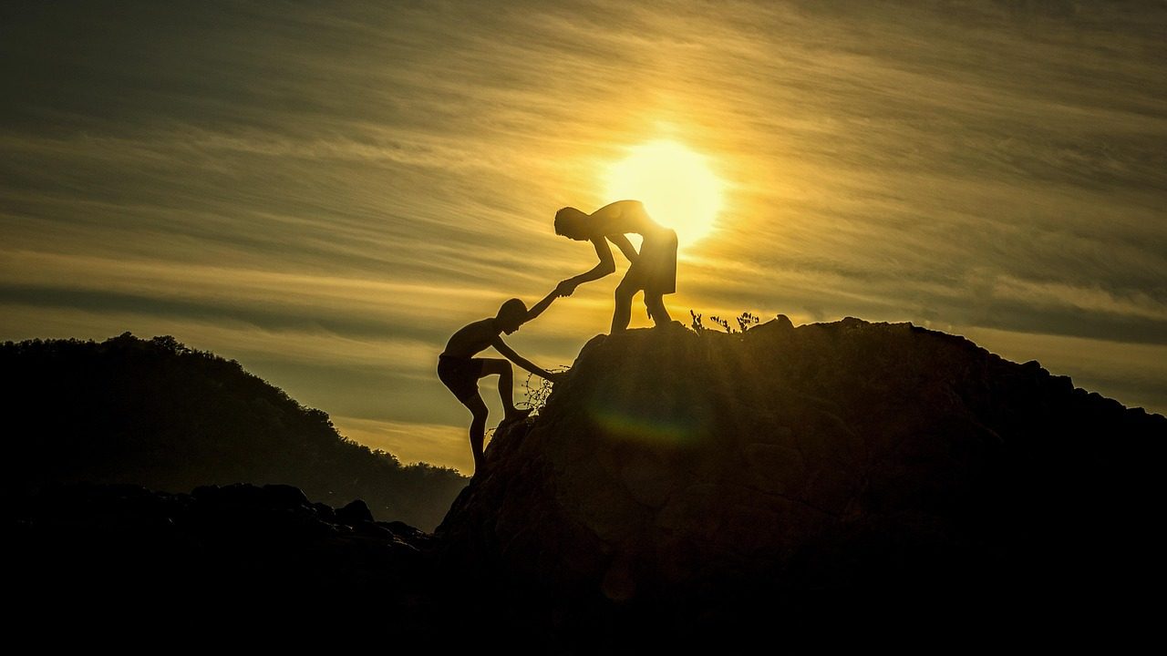 A rescue worker in safety gear rappelling down a rocky coastal cliff face during a training exercise.