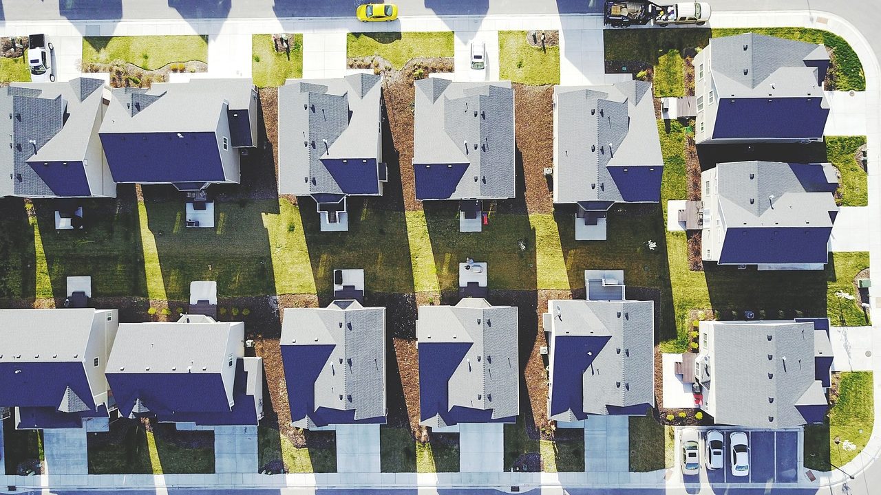 Aerial view of a suburban residential neighborhood with tree-lined streets and houses.