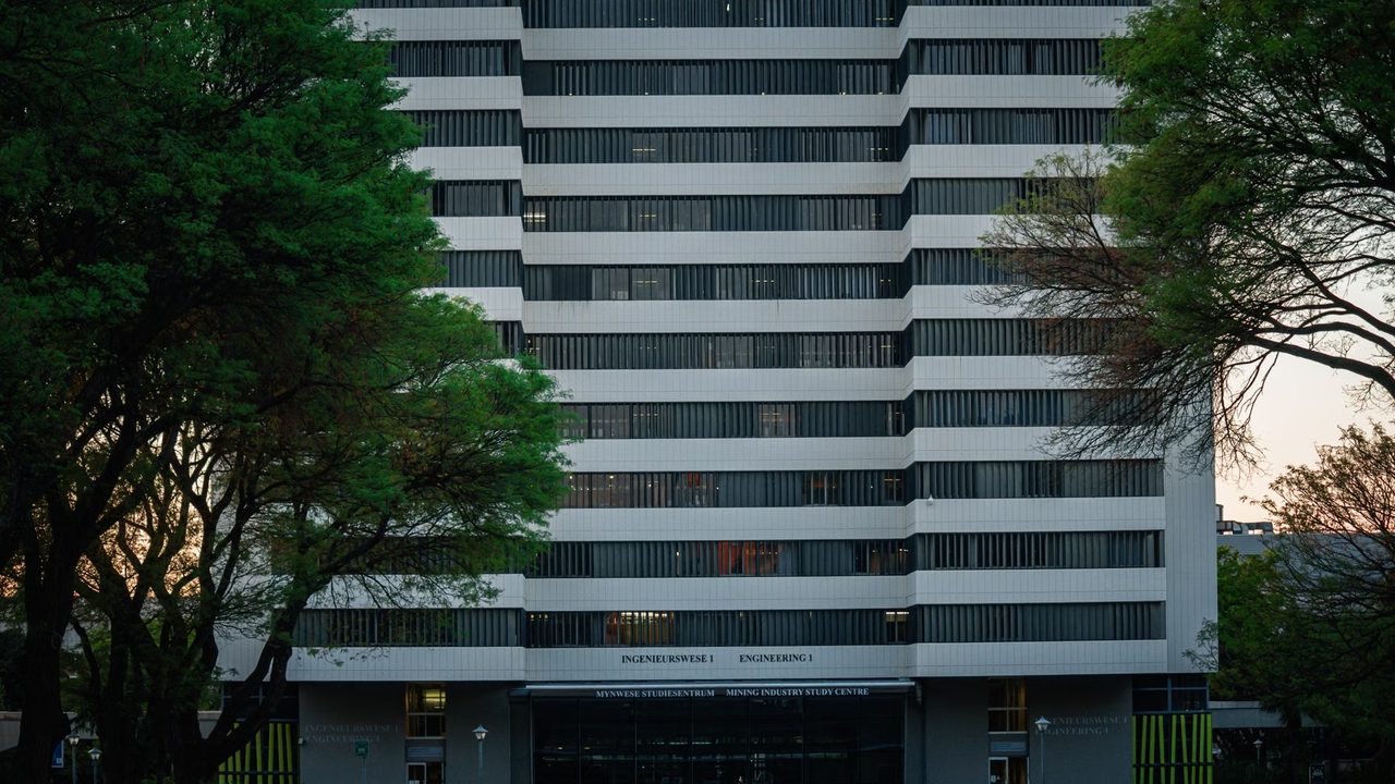 Modern university campus building with glass facade surrounded by open walkways.