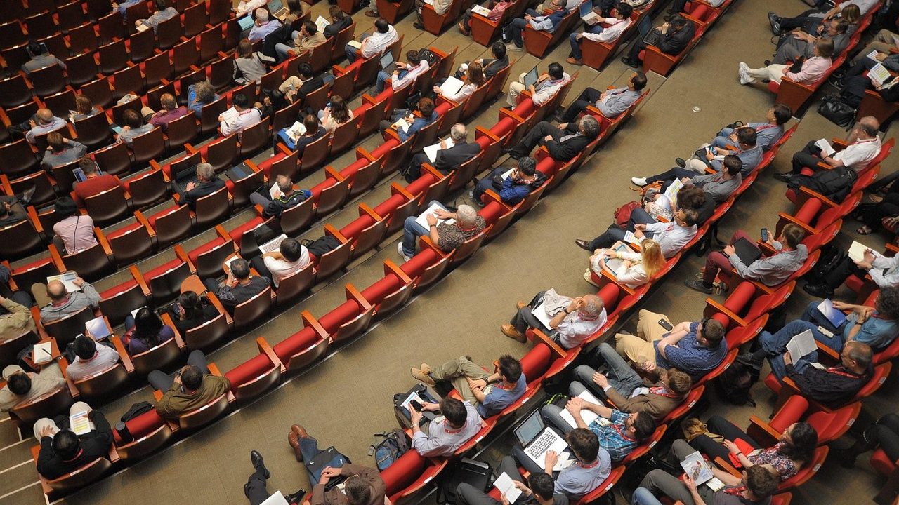 Empty government chamber with tiered seating, microphones, and official signage.