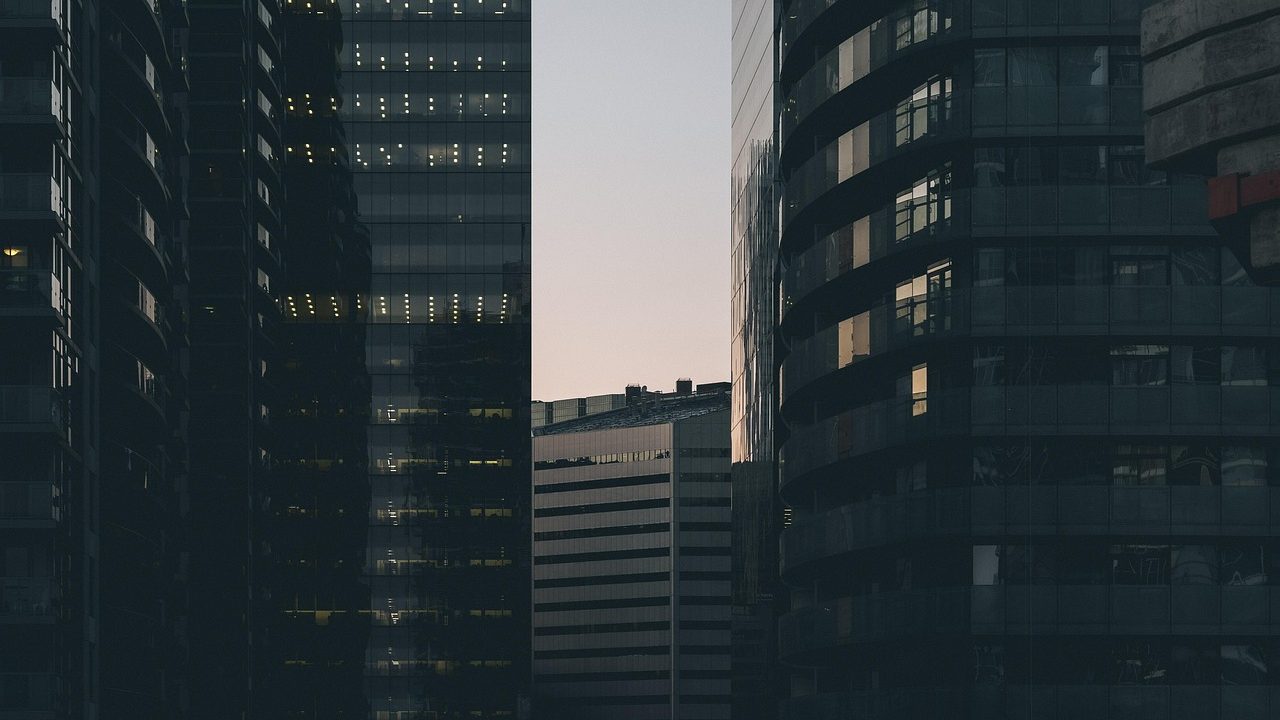 Glass-and-steel commercial towers reflecting sunlight in a dense urban business district.